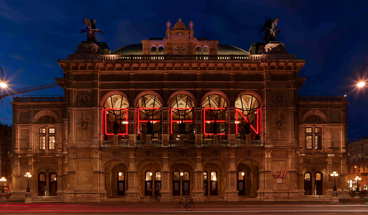 »<em>Offen</em>« — eine Installation des Österreichers Alexander Kada. »<em>Offen</em>«, eine temporäre Lichtinstallation auf der Fassade der Wiener Staatsoper, war ursprünglich als visuelles Zeichen zum Beginn der neuen Saison gedacht. Eine Einladung an die Stadt; eine Einladung an alle. Durch <abbr>COVID-19</abbr> wuchs ihm eine neue und grundlegende Bedeutung zu: Im Haus am Ring werden seit 19. Mai 2021 wieder Oper und Ballett gespielt. © Wiener Staatsoper GmbH/Michael Pöhn