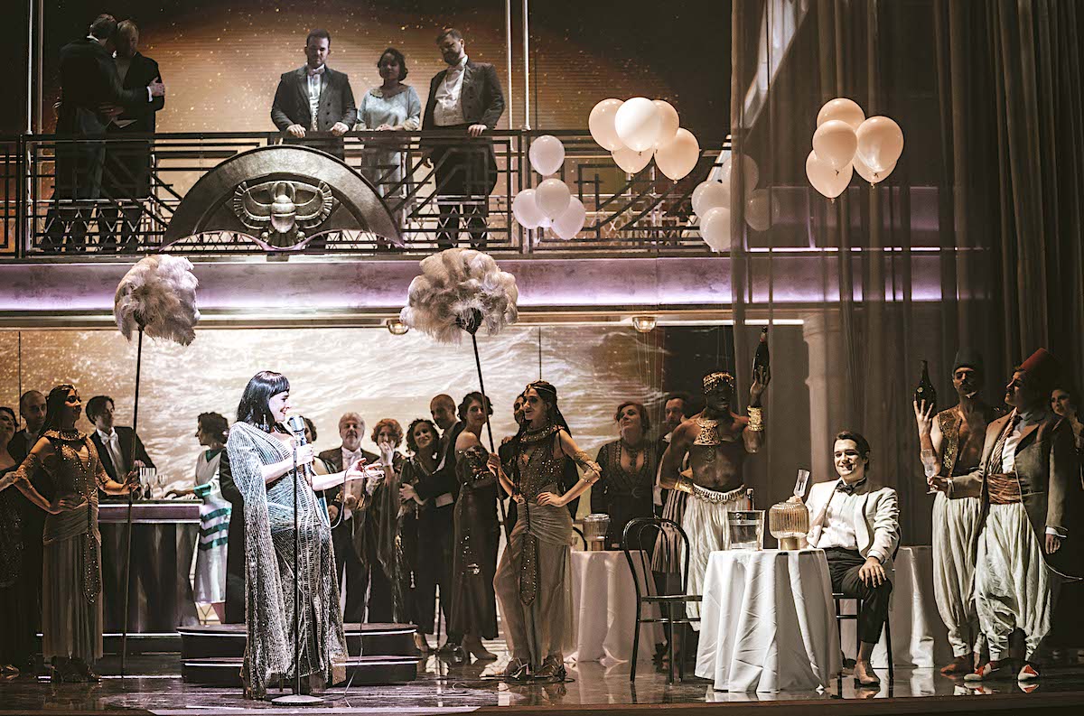 » Giulio Cesare in Egitto «, 2. Akt: Cecilia Bartoli (Cleopatra), Carlo Vistoli (Giulio Cesare) und das Ensemble beim » Captain’s Dinner « in Davide Livermores Inszenierung © OMC — Marco Borelli